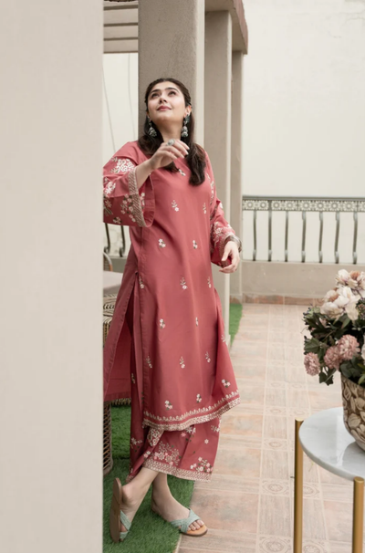A woman in a pink dress stands gracefully on a balcony